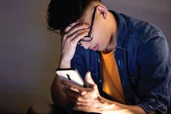 Young man looking at phone - Photo by asylsun/Shutterstock.com